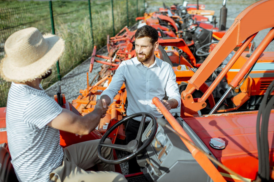 Ein junger Agronom wählt einen gebrauchten Traktor für die Landwirtschaft aus
